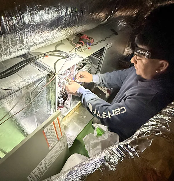 Technician working in the attic on a customer's unit.
