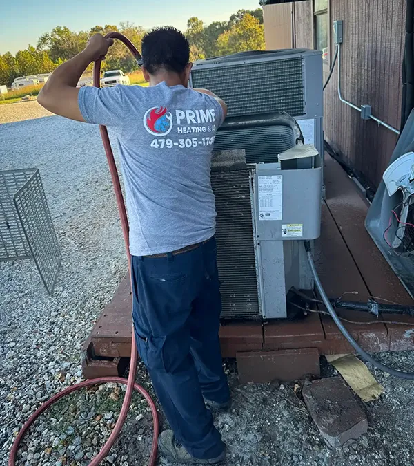A Prime Heating & Air technician performs routine maintenance on a customer's HVAC.